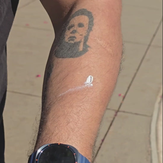 Hispanic man with tattoos showing the application of sunblock on his skin