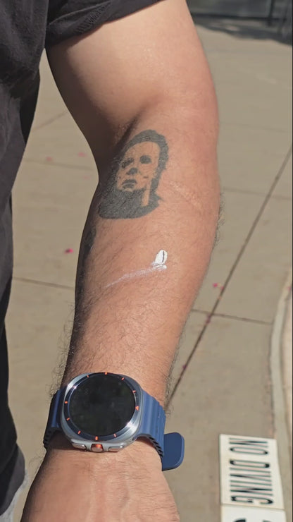 Hispanic man with tattoos showing the application of sunblock on his skin